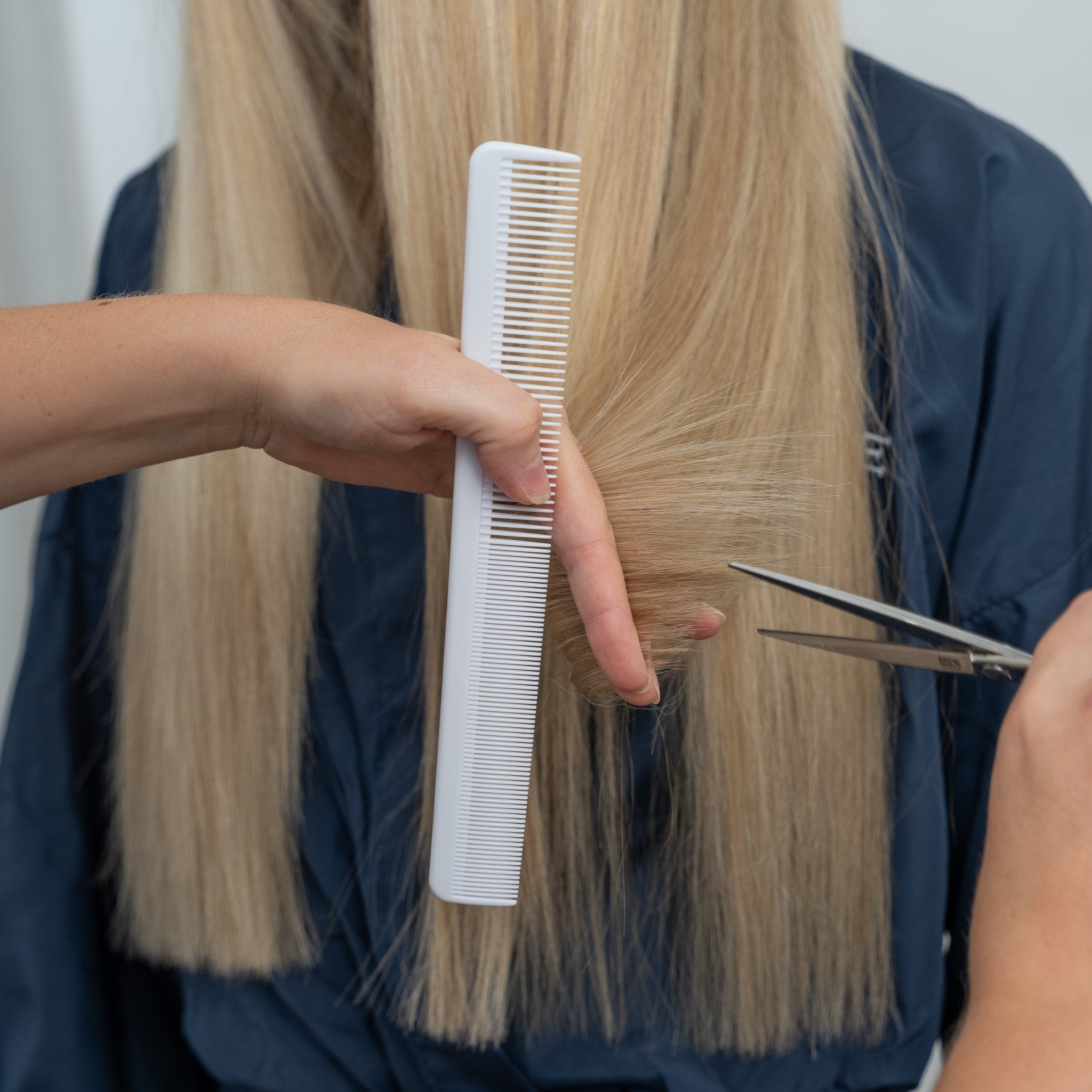  Hair stylist combing and trimming long blonde hair extensions 